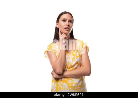 femme brune confiante européenne avec les cheveux lâches portant un t-shirt jaune sur un fond blanc avec espace copie Banque D'Images