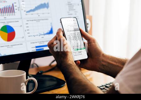 Homme utilisant l'application Sheets sur un téléphone mobile et un ordinateur portable. Google Workspace, outils de productivité numérique en ligne. À l'aide d'une feuille de calcul. Banque D'Images