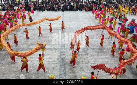 Pékin, Chine. 22 février 2024. Une photo de drone aérien prise le 22 février 2024 montre des gens regardant danser le dragon pour célébrer le prochain Festival des lanternes dans le comté de Hezheng, dans la province du Gansu, au nord-ouest de la Chine. Le Festival des lanternes tombe le 24 février cette année. Crédit : Shi Youdong/Xinhua/Alamy Live News Banque D'Images