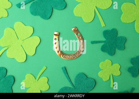 Prog La journée de Patrick. Fer à cheval doré et feuilles de trèfle décoratives sur fond vert, pose plate Banque D'Images