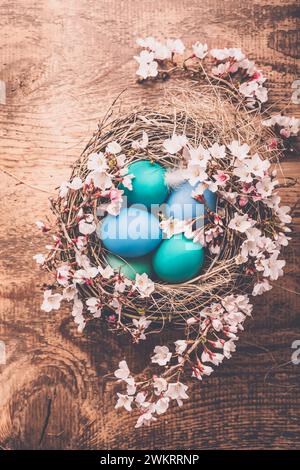 Fond de Pâques avec des oeufs colorés dans le nid sur fond en bois Banque D'Images