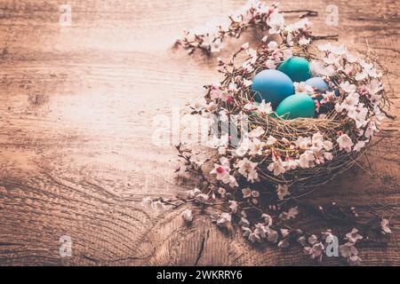 Fond de Pâques avec des oeufs colorés dans le nid sur fond en bois Banque D'Images