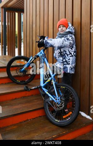 Un garçon en vêtements d'hiver fait du vélo pendant les vacances Banque D'Images