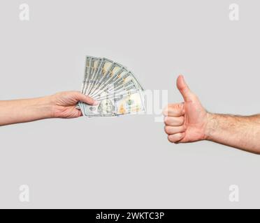 Fan de dollars dans la main de la femme et la main de l'homme avec le pouce vers le haut. Concept de symbole de réussite commerciale. Banque D'Images