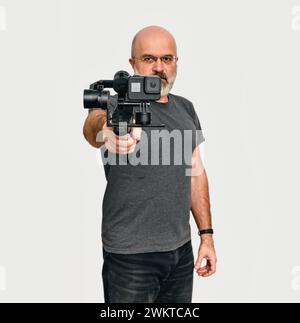 L'homme tient un stabilisateur vidéo-photo portable moderne. Fond blanc. Vlog et concept de blog vidéo Banque D'Images