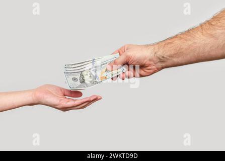 Main masculine envoie les billets de banque à la main de la femme. Transfert d'argent, parrainage, relations financières. Banque D'Images