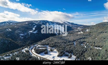 Vue aérienne route de circulation à travers les montagnes enneigées avec des pins Banque D'Images