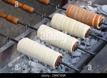 Trdelník aussi appelé trozkol est une sorte de gâteau à la broche d'Europe de l'est cuit lentement sur des braises et servi avec des grains de fruits secs ou de sucre Banque D'Images