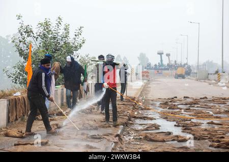 Frontière de Shambhu, Pendjab, Inde. 21 février 2024. Un homme pulvérise l’eau sur des sacs de jute pour lutter contre les coquilles lacrymales utilisées par les autorités. Les agriculteurs indiens se rassemblent sur le site de la manifestation alors qu'ils marchent vers New Delhi pour faire pression pour obtenir de meilleurs prix des récoltes qui leur ont été promis en 2021, à la barrière de Shambhu, un poste frontière entre les états du Pendjab et du Haryana, Inde, le 21 février 2024. (Crédit image : © Rohit Lohia/ZUMA Press Wire) USAGE ÉDITORIAL SEULEMENT! Non destiné à UN USAGE commercial ! Banque D'Images