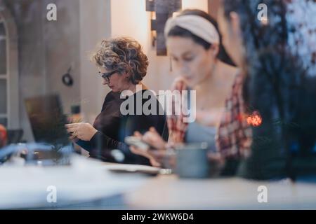 Une femme utilise attentivement son téléphone intelligent au milieu d'un environnement de travail, symbolisant la connectivité et le multitâche dans un espace d'entreprise. Banque D'Images