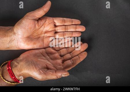 Gros plan des mains ouvertes d'une femme âgée sur un fond noir. Banque D'Images