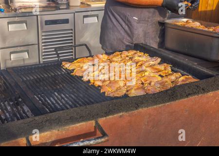 Gros plan du chef dans un restaurant en plein air, plaçant un lot de viande fraîche sur le gril. Banque D'Images