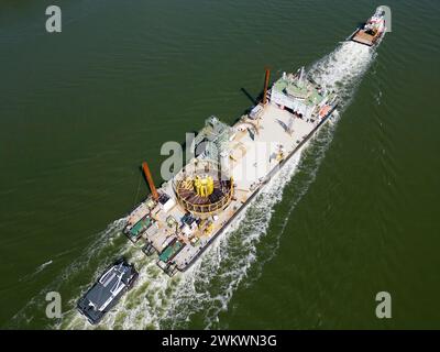 Transport d'un grand câble enroulé sur un cadre rond vers un parc éolien offshore. Après la construction et enterré dans les fonds marins, le câble fournira de l'électricité au continent Banque D'Images