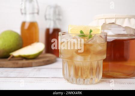 Savoureux kombucha et glaçons en verre sur une table en bois blanc, gros plan. Espace pour le texte Banque D'Images