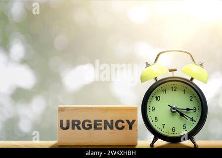 Le réveil avec texte d'urgence sur le bloc de bois sur la table. Concept d'urgence Banque D'Images
