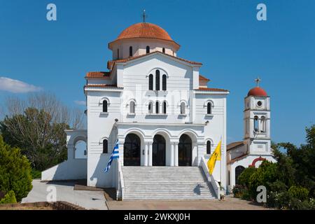 Une église blanchie à la chaux avec un toit rouge et un dôme sous un ciel bleu clair, église orthodoxe grecque de la Transfiguration du Sauveur, Porto Lagos Banque D'Images