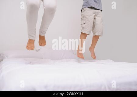 Saut, lit et enfants avec des jambes, de l'énergie et le matin dans une chambre avec jeu et pieds. Jeunesse, frère et sœur et maison avec un enfant excité sur couette en air avec Banque D'Images