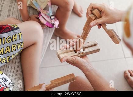 Les tweens et un adulte jouant des jouets de blocs de construction en bois ensemble dans un intérieur minimaliste léger Banque D'Images