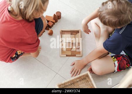 Un tweens jouant des jouets de blocs de construction en bois ensemble dans un intérieur minimaliste léger Banque D'Images