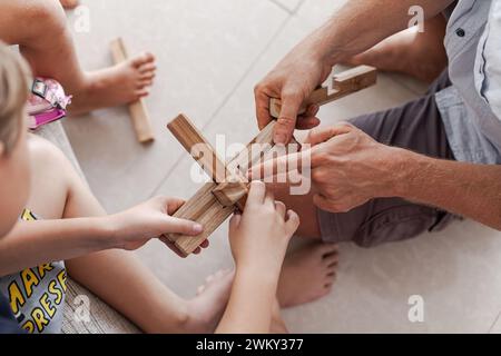 Les tweens et un adulte jouant des jouets de blocs de construction en bois ensemble dans un intérieur minimaliste léger Banque D'Images