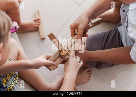 Les tweens et un adulte jouant des jouets de blocs de construction en bois ensemble dans un intérieur minimaliste léger Banque D'Images