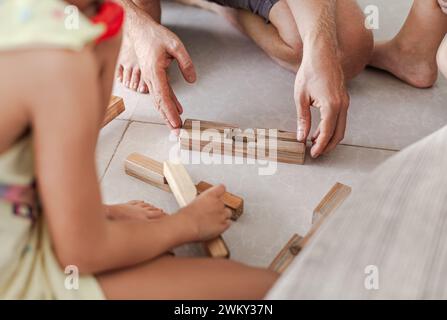 Les tweens et un adulte jouant des jouets de blocs de construction en bois ensemble dans un intérieur minimaliste léger Banque D'Images