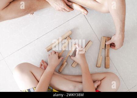 Les tweens et un adulte jouant des jouets de blocs de construction en bois ensemble dans un intérieur minimaliste léger Banque D'Images