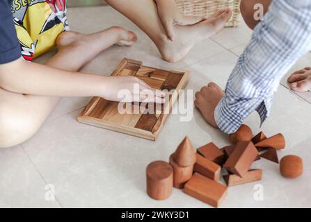 Les tweens et un adulte jouant avec des jouets de blocs de construction en bois ensemble dans un intérieur minimaliste léger Banque D'Images