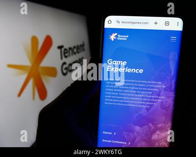 Personne tenant un smartphone avec le site Web de la société chinoise de jeux vidéo Tencent Games devant le logo. Concentrez-vous sur le centre de l'écran du téléphone. Banque D'Images