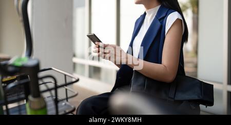 Femme d'affaires commuter son vélo aller au bureau de travail, femme d'affaires asiatique assis rue latérale avec vélo et à l'aide d'un smartphone Banque D'Images