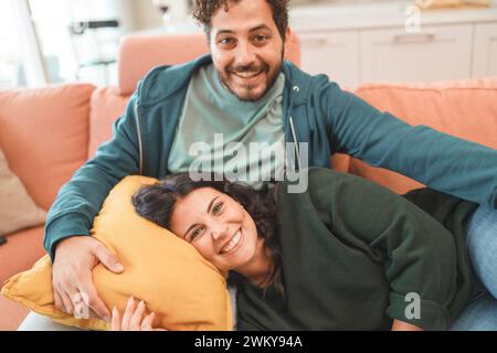 Un couple heureux partage un moment confortable et affectueux tout en se relaxant sur un canapé confortable à la maison - style de vie domestique paisible et intime - newlyw Banque D'Images