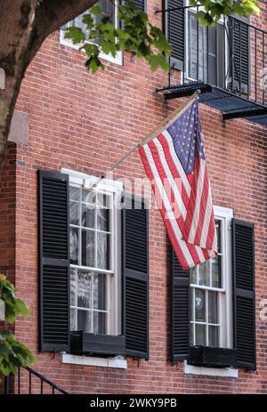 Un drapeau américain suspendu à l'extérieur D'Une maison de ville traditionnelle Brownstone dans la région de Beacon Hill à Boston Banque D'Images