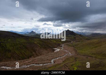 Paysage islandais spectaculaire avec des montagnes verdoyantes couvertes d'épaisse mousse islandaise et de rivière par une journée nuageuse grise et sombre. Islande aventure randonnée Lauga Banque D'Images