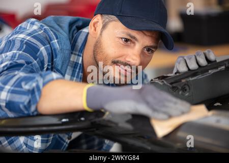 mécanicien préparant la carrosserie de voiture à l'aide de papier abrasif Banque D'Images