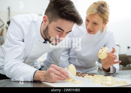 jeune confiseur décorant des oeufs en chocolat fantaisie Banque D'Images