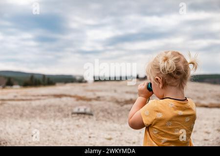 Enfant regardant à travers des jumelles au parc national de Yellowstone la Banque D'Images