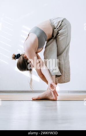 Femme en pantalon en lin faisant la pose de pliage avant de yoga créatif Banque D'Images