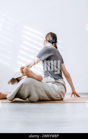 Femme en vêtements décontractés pratiquant le yoga sur tapis de liège à la maison Banque D'Images