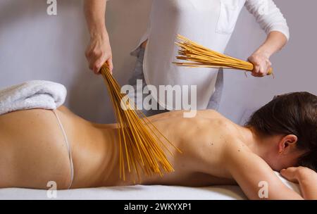 Massage du dos dans la salle de massage avec balais en bambou. Massothérapeute massant le dos de la femme avec bambou.vue latérale horizontale, massage relaxant concp Banque D'Images