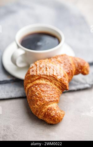 Croissant savoureux cuit et tasse à café sur la table de la cuisine. Banque D'Images