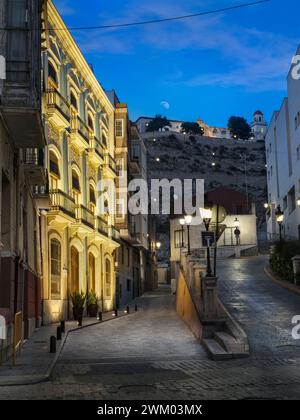 Les lampadaires clignotent alors que la lune se lève au-dessus d'une rue déserte à Orihuela, Alicante, Espagne. Banque D'Images