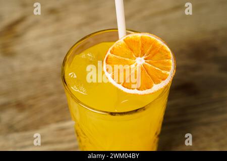 Un cocktail avec une tranche d'orange séchée et de la glace sur une table en bois Banque D'Images