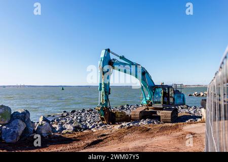 Une excavatrice bleue Kobelco SK350 sur le front de mer travaille sur les défenses côtières à Southsea, Portsmouth, une station balnéaire sur le Solent, côte sud de l'Angleterre Banque D'Images