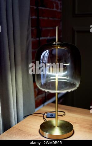 Une lampe design intéressante sur une base dorée avec un verre épais. Style anglais. Intérieur classique Banque D'Images