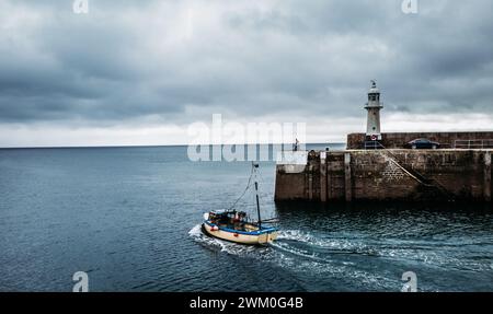 Un bateau naviguant près d'un phare et d'un quai sur l'eau, Mevagissey, Royaume-Uni Banque D'Images