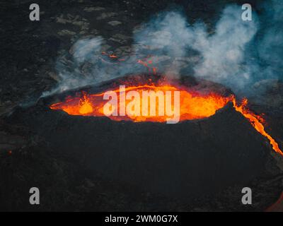 Lave coulant, magma chaud se déversant du cratère du volcan, vue latérale aérienne. Concepts d'éruption volcanique et terre islandaise de feu et de glace. Banque D'Images