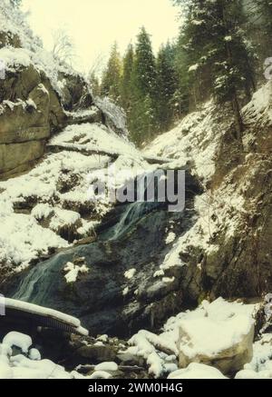 Une petite cascade non gelée coule dans les rochers des montagnes d'hiver Banque D'Images