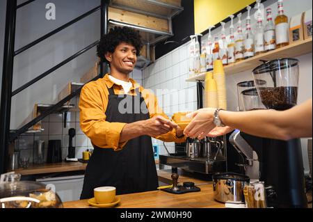 Barista souriant servant du café au client au café Banque D'Images