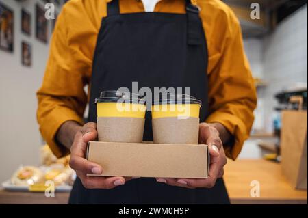 Barista tenant des tasses à café à emporter au café Banque D'Images