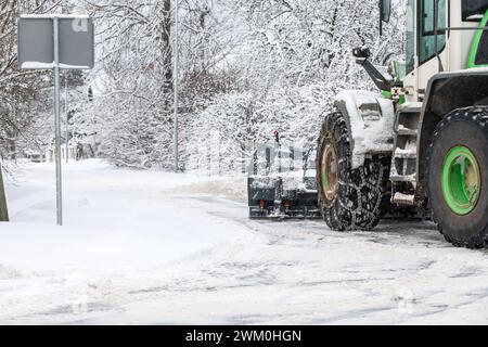 Tracteur dégage la neige de la route après les chutes de neige, chaînes sur la roue du tracteur, paysage hivernal. Banque D'Images